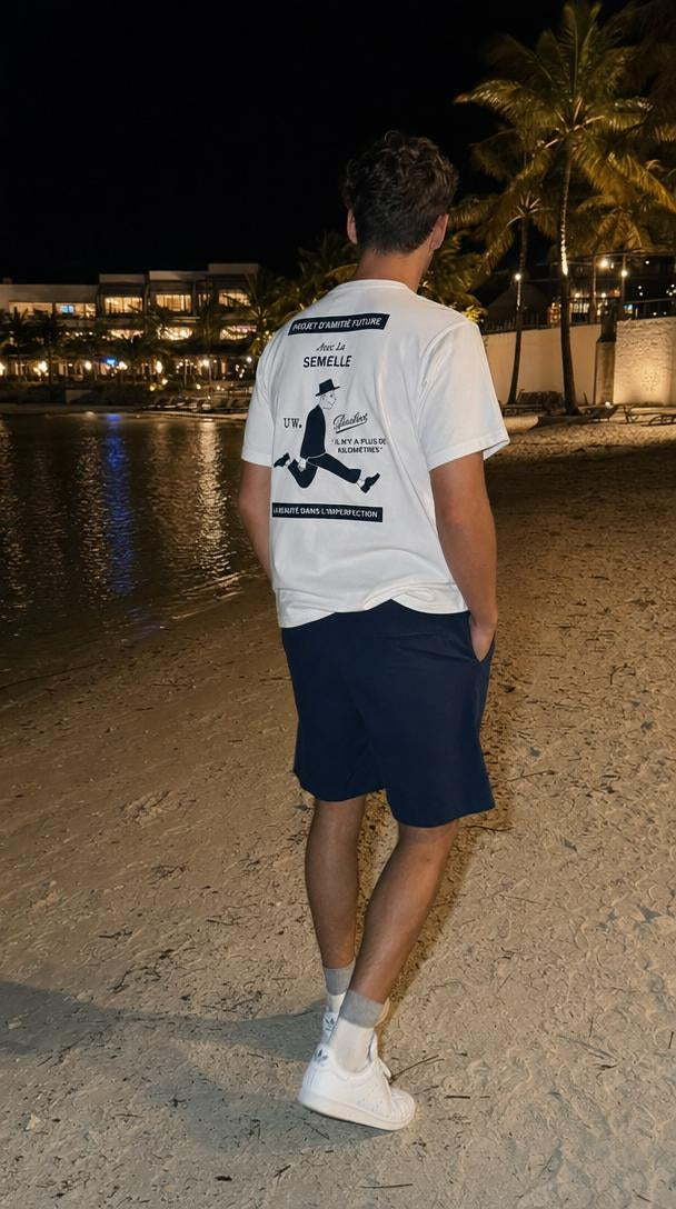 Outfit uomo estivo casual: t-shirt ecru, shorts blu e Stan Smith bianche